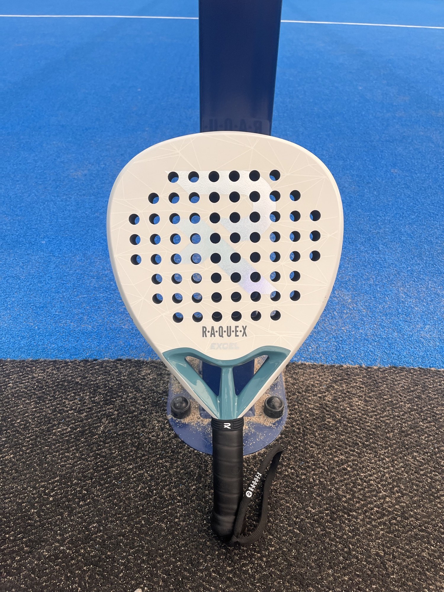 White Raquex Excel teardrop racket on a court net post