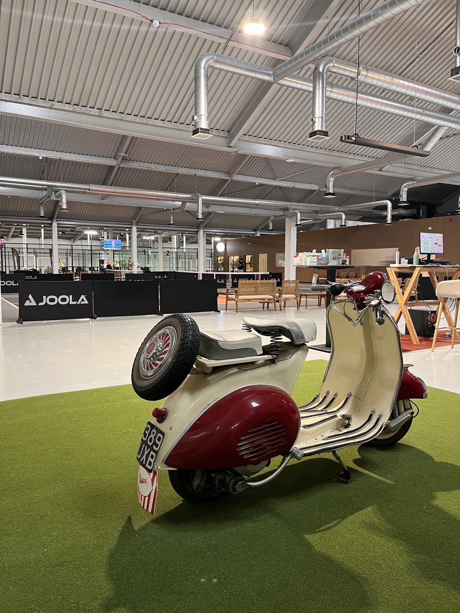 A vintage cream and oxblood Vespa parked on indoor astroturf
