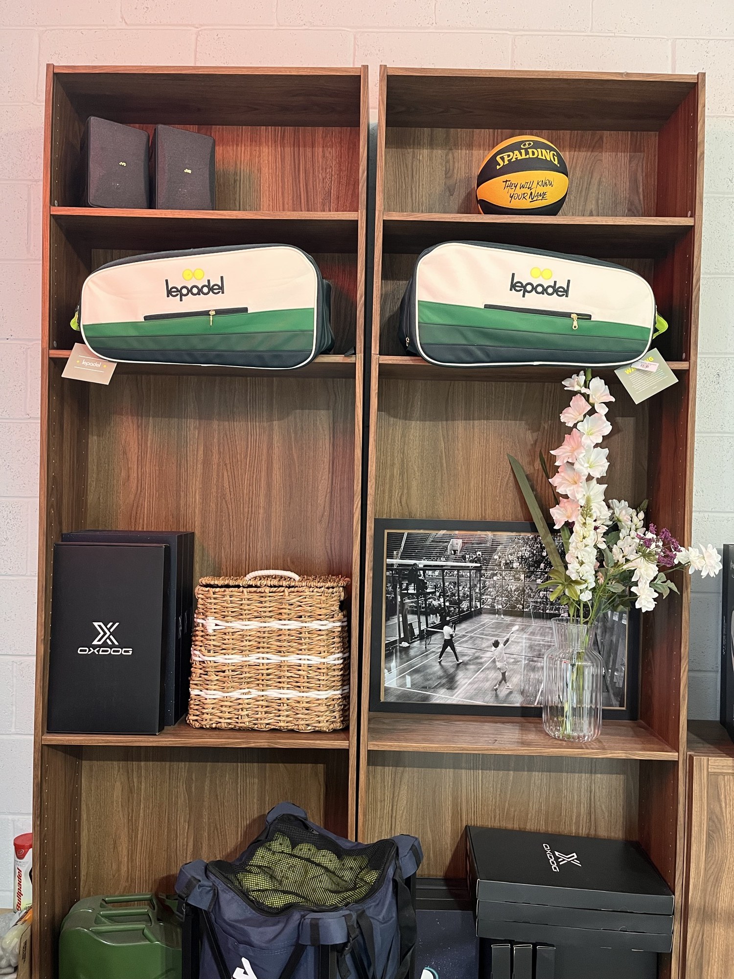 Walnut shelving with padel bags, a basketball and a framed print