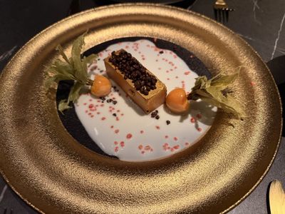 A bar of foie on a gold plate, with white chocolate cream, physalis and popping candy