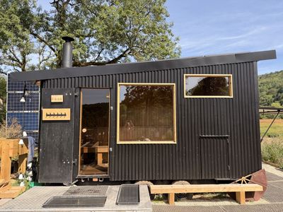 A black wood-fired sauna cabin on a trailer beside the River Avon at Warleigh Weir
