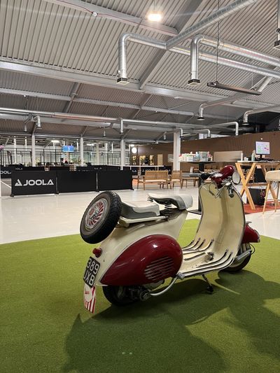 A vintage cream and oxblood Vespa parked on indoor astroturf