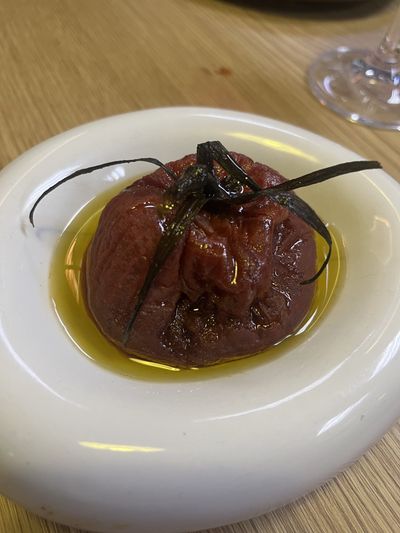 A whole tomato confited with miso, dark and glossy in olive oil