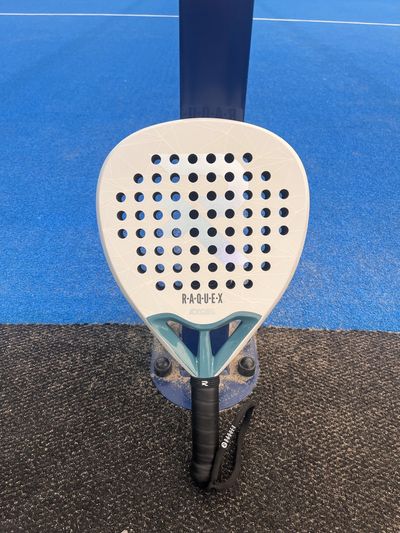 White Raquex Excel teardrop racket on a court net post